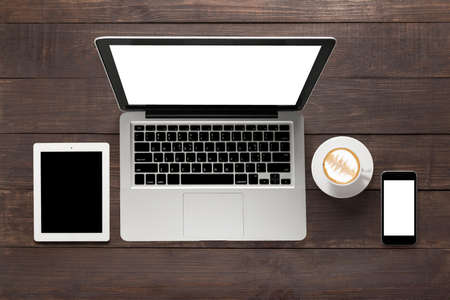 Laptop, tablet, smartphone and a cup of coffee on wooden background.の写真素材
