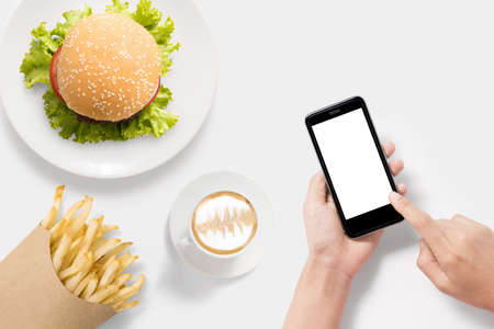 Design concept of mockup using smartphone with burger, french fries and coffee set isolated on white background. Clipping Path included on white background.の写真素材