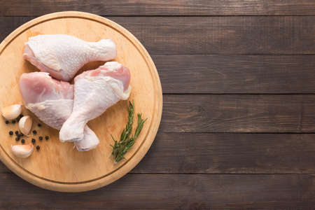 Raw chicken drumsticks on cutting board on wooden background. Copy space for your text.の写真素材