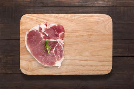 Top view raw pork chop steak on cutting board on wooden background. Copyspace for your text.の写真素材
