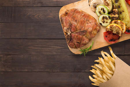 Grilled pork chop and chips on the wooden background. Copyspace for your text.の写真素材