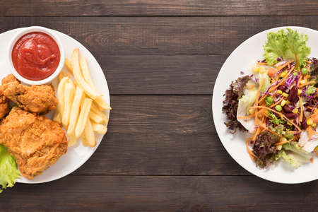 Fresh salad and Fried chicken and french fries on the wooden background. contrasting food.の写真素材