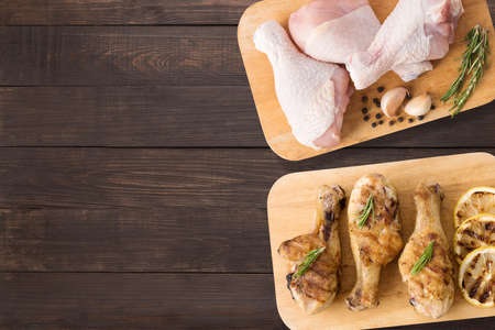 Top view raw chicken and grilled chicken on cutting board on wooden background. Copyspace for your text.の写真素材