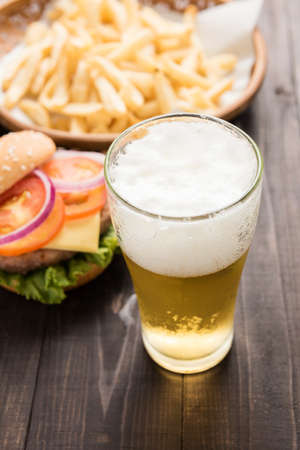beer being poured into glass with gourmet hamburgers and french fries.の写真素材