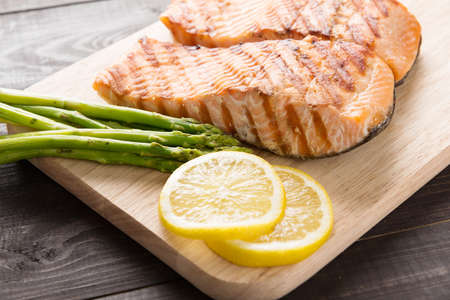 Grilled salmon with lemon, asparagus on the wooden table.の写真素材