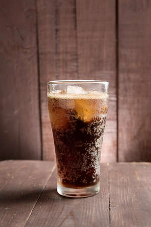 Cola in glass with ice on wooden background.の写真素材
