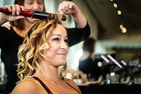 Young Gorgeous Smiling Female Getting Hair Curledの写真素材