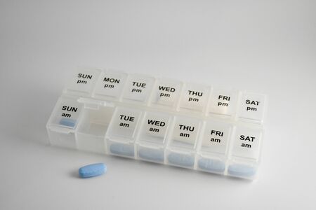 Close up shot of a transparent pill box with several compartments for the days of the week.の写真素材