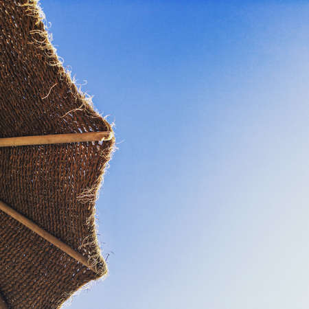 Straw beach umbrella with a blue sky backgroundの写真素材
