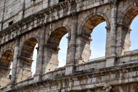 Detail of the famous Italian Colosseum monument in Rome, built in marble, with a blue sky backgroundの写真素材