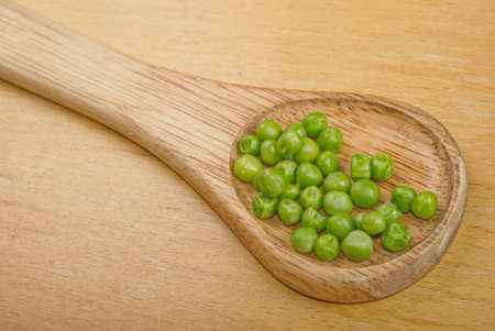 Boiled peas in spoon on wooden backgroundの写真素材