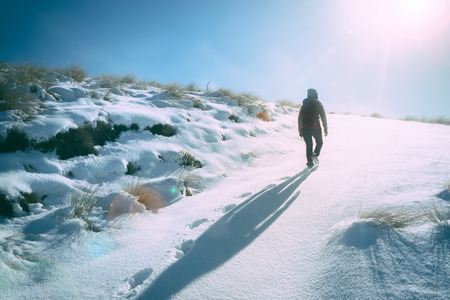 Girl walking in to sun light on winter trackの写真素材