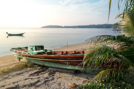 Old broken longtail boat on the Thai beach during the sunsetの写真素材