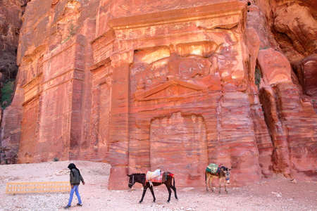 PETRA, JORDAN - MARCH 7, 2016: Colorful tombs in the Outer Siq with a local Bedouin leading his donkeysのeditorial素材