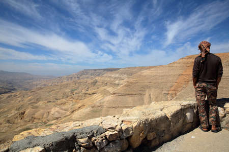WADI MUJIB, JORDAN - MARCH 6, 2016: A young Jordanian man looking at Wadi Mujib Canyon from Kings Roadのeditorial素材