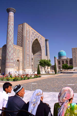 SAMARKAND, UZBEKISTAN - MAY 21, 2011: The Registan with Uzbek men and women traditionally dressed in the foregroundのeditorial素材