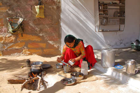 SUMRASAR, GUJARAT, INDIA - DECEMBER 19, 2013: Woman preparing thali (indian food) in the courtyard of a house in Sumrasar, local village near Bhujのeditorial素材