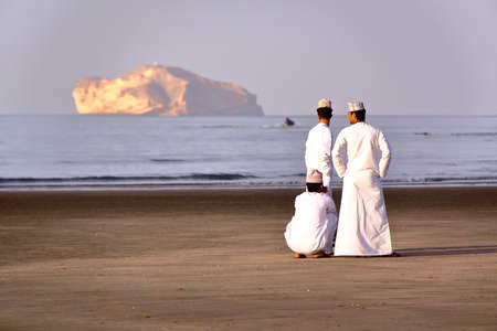 MUSCAT, OMAN - FEBRUARY 9, 2012: Three Omani men traditionally dressed on the main beach in Central Muscatのeditorial素材