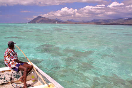 TAMARIN BAY, MAURITIUS - NOVEMBER 23, 2012: A fisherman on his boat in Tamarin Bayのeditorial素材