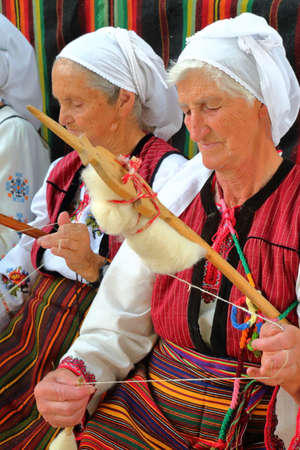 BANSKO, BULGARIA - JULY 25, 2015: Women traditionally dressed spinning woolのeditorial素材