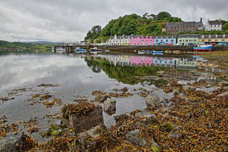 View of Portree harbor with reflections and colorful houses, seen from the seashore, Isle of Skye, Highlands, Scotland, UKの写真素材
