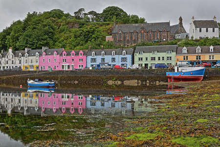 ISLE OF SKYE, UK - JUNE 19, 2017: View of Portree harbor with reflections and colorful houses, seen from the seashore, Highlands, Scotlandのeditorial素材
