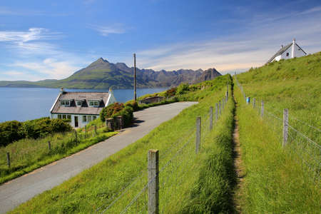 ISLE OF SKYE, UK - JUNE 20, 2017: View of the Black Cuillin mountain range across Loch Scavaig from the coastal path near Elgol with traditional houses in the foregroundのeditorial素材