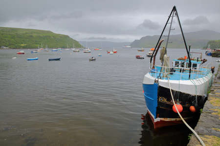 ISLE OF SKYE, UK - JUNE 18, 2017: View of Portree Bay from Portree Harbor with a commercial fishing boat in the foreground, Highlands, Scotlandのeditorial素材