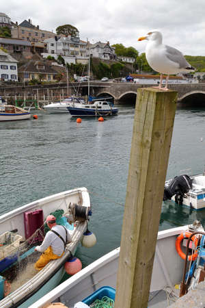 LOOE, CORNWALL, UK - MAY 17, 2015: Looe fishing port with a fisherman working on his fishing netのeditorial素材