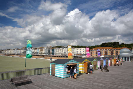 HASTINGS, UK - JULY 23, 2017: View of the seafront from the Pier (rebuilt and open to public in 2016) with colorful huts in the foreground and a beautiful cloudy skyのeditorial素材
