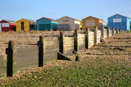 WHITSTABLE, UK - OCTOBER 15, 2017: A row of colorful wooden Huts overlooking the sea with breakwater...