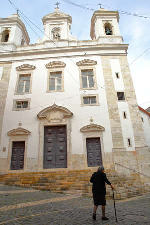LISBON, PORTUGAL - NOVEMBER 2, 2017: An old local woman walking in front of Sao Miguel Church in Alfama neighborhoodのeditorial素材