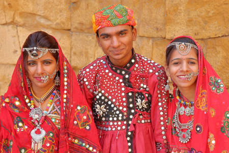 JAISALMER, RAJASTHAN, INDIA - DECEMBER 21, 2017: Portrait of a young man and two young women dressed traditionally with colorful clothes and jewelsのeditorial素材