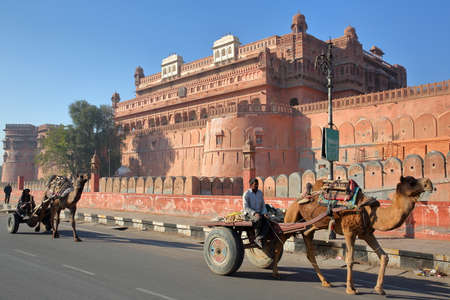 BIKANER, RAJASTHAN, INDIA - DECEMBER 23, 2017: 2 carriages with camels in front of Junagarh Fortのeditorial素材
