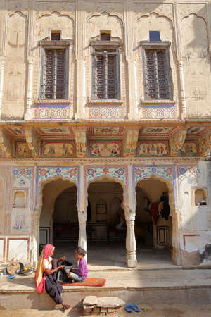 MANDAWA, RAJASTHAN, INDIA - DECEMBER 27, 2017: Chokani Double Haveli with frescoes and a woman with her child in the foregroundのeditorial素材