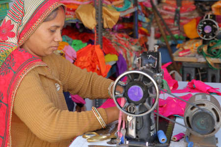 CHITTORGARH, RAJASTHAN, INDIA - DECEMBER 13, 2017: Close-up on a tailor woman working on her sewing machine inside her shop in the Old Townのeditorial素材