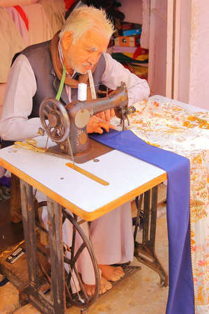 CHITTORGARH, RAJASTHAN, INDIA - DECEMBER 13, 2017: Close-up on an old tailor man working on his...