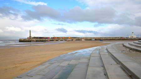 The beach at low tide by stormy and windy weather with Margate Harbor Arm in the background, Margate, Kent, UKの写真素材