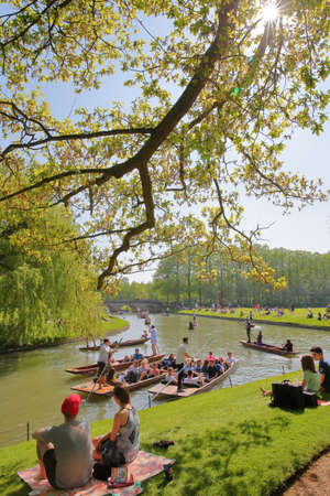 CAMBRIDGE, UK - MAY 6, 2018: Students enjoying a sunny day on the banks of the river Cam at St John's College University with tourists and students puntingのeditorial素材