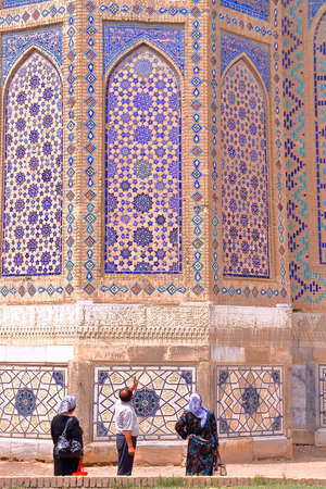 SAMARKAND, UZBEKISTAN - MAY 19, 2011: Local Uzbek tourists observing the architectural details of...