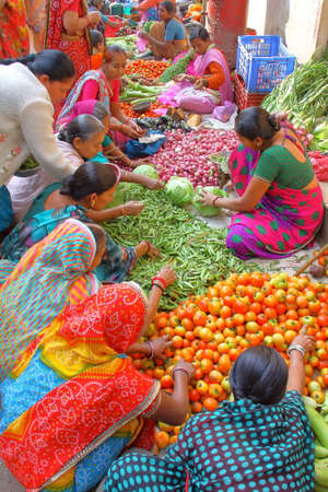 PALITANA, GUJARAT, INDIA - DECEMBER 31, 2013: Vegetable market with women wearing colorful sarisのeditorial素材