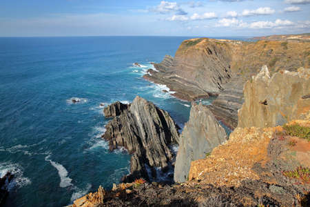 Dramatic and colorful cliffs on Alentejo West Coast at Cabo Sardao, Alentejo, Portugal, with white storks nesting at the top of the rocky cliffsの写真素材