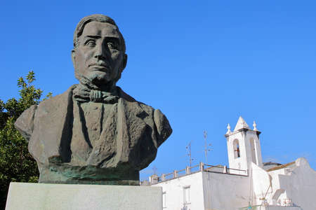 TAVIRA, PORTUGAL - NOVEMBER 20, 2018: The statue of Francisco Manuel Alvares Botelho (1803 â 1875) with the whitewashed catholic church Sao Bras in the backgroundのeditorial素材