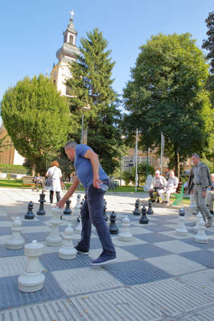 SARAJEVO, BOSNIA AND HERZEGOVINA - SEPTEMBER 15, 2019: Local chess players gathering in Trg Oslobodenja (Liberation Square) and playing with a large scale Chess Board, with the Orthodox Cathedral of the Nativity of the Theotokos in the backgroundのeditorial素材