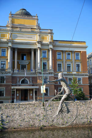 SARAJEVO, BOSNIA AND HERZEGOVINA - SEPTEMBER 13, 2019: Sculpture (designed by Enes Sivac in 1993) hanging over the Miljacka river, with the University Faculty of Law in the backgroundのeditorial素材