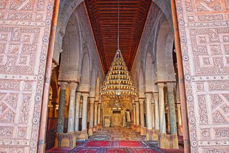 KAIROUAN, TUNISIA - DECEMBER 10, 2019: The entrance to the prayer room of the Great Mosque of Kairouan, with the carved wooden door in the foregroundのeditorial素材
