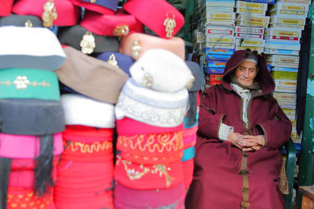 TUNIS, TUNISIA - JANUARY 02, 2020: A chechia shop (traditional hats) located in the souk inside the medina, with a focus on a seller traditionally dressedのeditorial素材