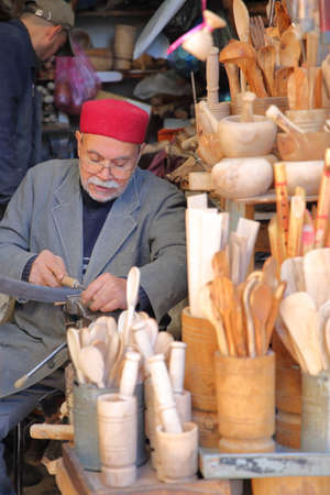 SFAX, TUNISIA - DECEMBER 24, 2019: A craftsman at work in the souk inside the medina. He is wearing a chechia (traditional hat)のeditorial素材