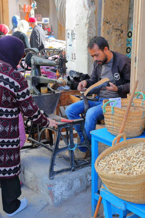 SFAX, TUNISIA - DECEMBER 25, 2019: A cobbler at work inside the medina with a sewing machineのeditorial素材