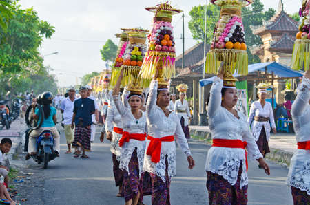 BALI - JUNE 25: Village women carry offerings of food baskets on their heads in a procession to the village temple June 25, 2012 in Bali, Indonesia.のeditorial素材